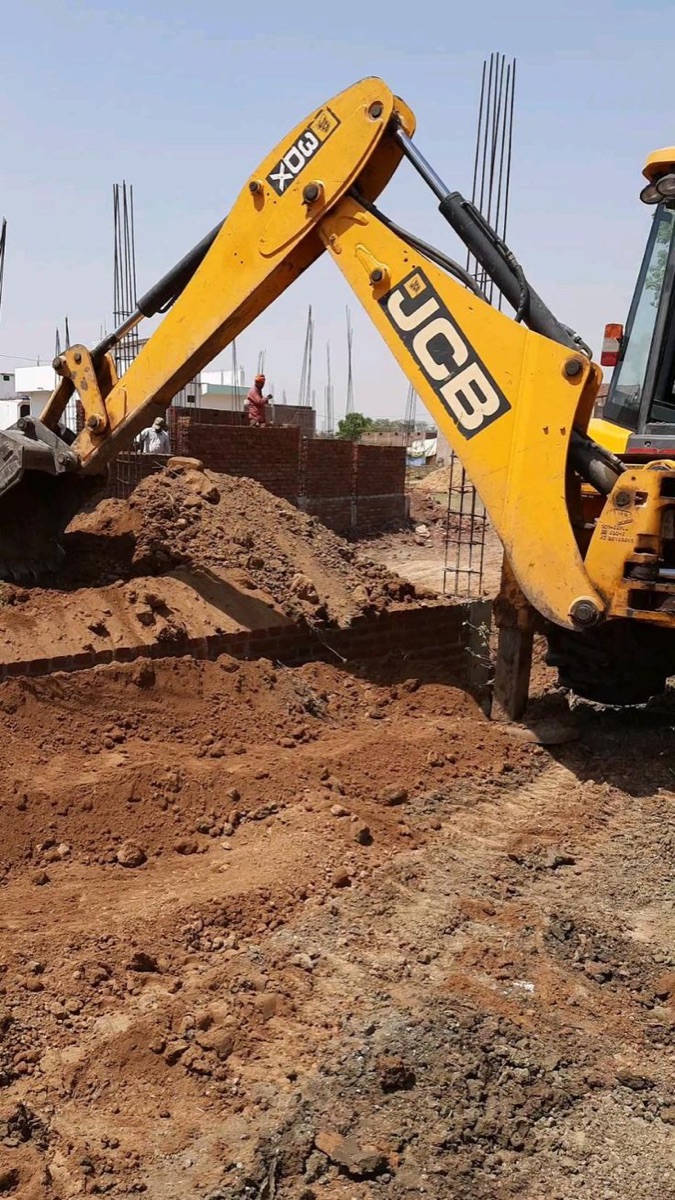 Excavator performing earthworks and backfilling at a foundation site