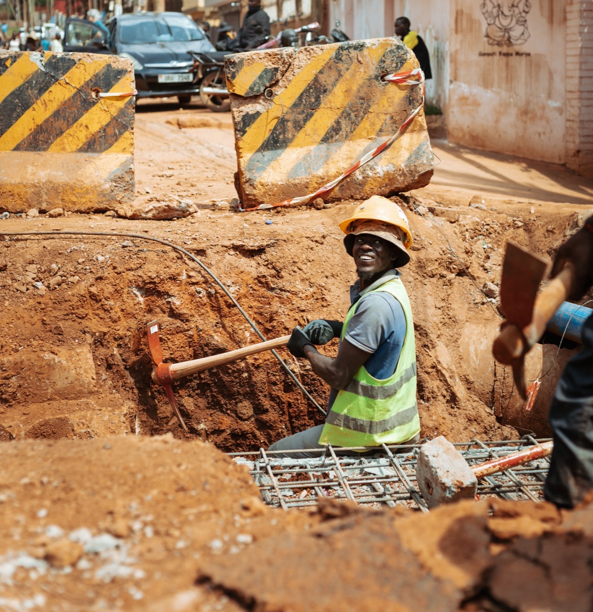 Worker excavating a foundation trench beside reinforced concrete formwork